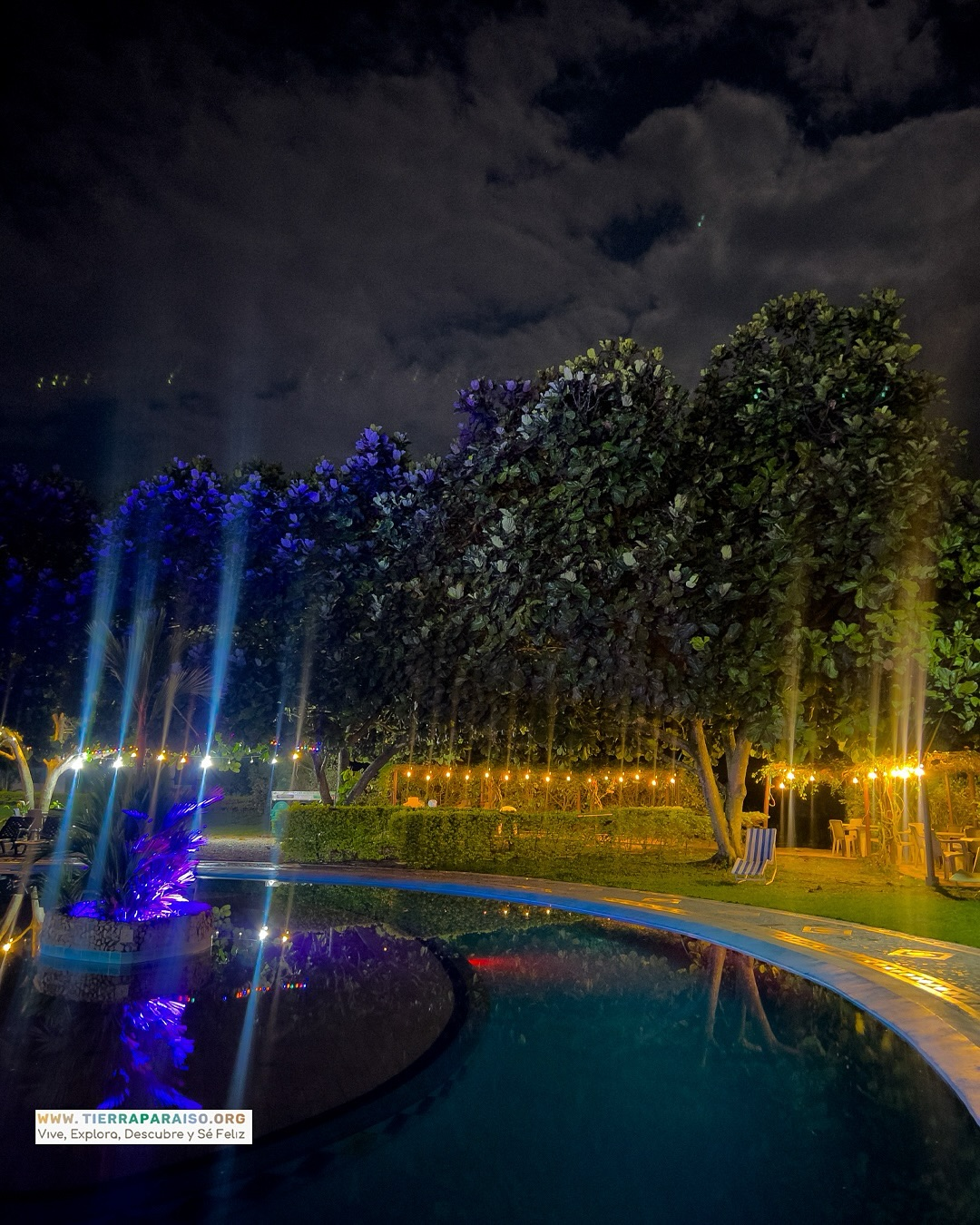 Piscina nocturna con luces y fuentes