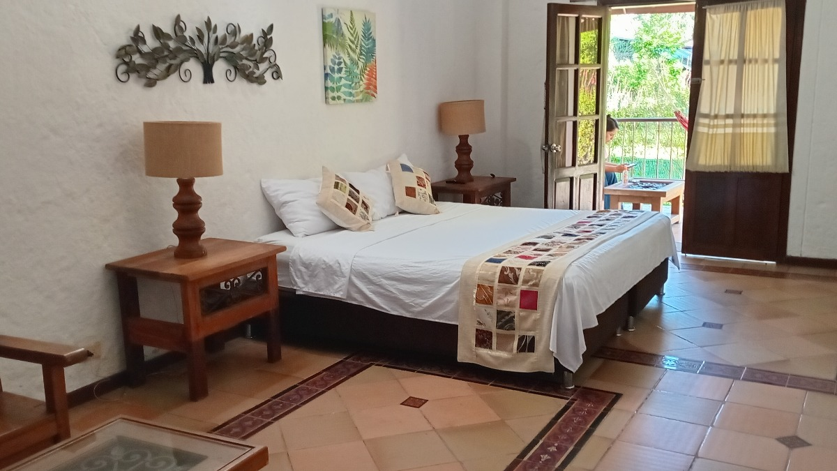 Suite Ejecutiva - cama y balcón con vista al jardín